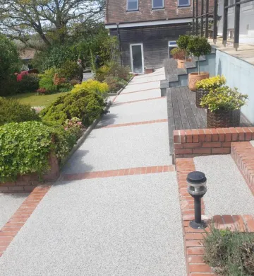 resin bound pathway through a garden in grey with brick edging