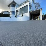 grey drive leading to large white house
